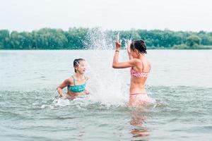 One girl splashes water on another in the river. Local tourism. Summer vacation photo