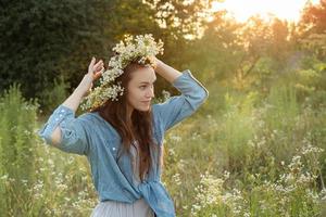 Beautiful girl  walking on field on summer with wildflowers. photo