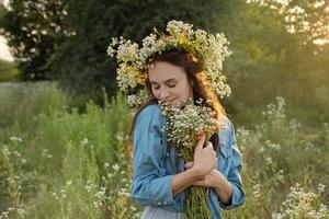 Beautiful girl  walking on field on summer with wildflowers. photo