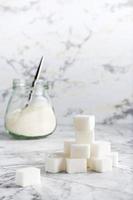 Sugar cubes and granulated sugar in a jar on the table. Vertical view photo