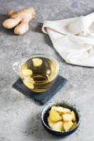 Ginger tea in a cup and chopped root in a bowl on the table. Natural Vitamins. Vertical view photo