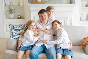 Happy caucasian family at home, cute son and daughter hugging dad, father photo