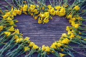 heart of yellow flowers on wooden background, love and romance concept, copy space photo