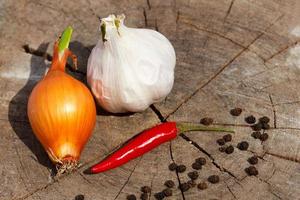 Head of garlic and red hot peppers on a wooden background close-up of a board photo