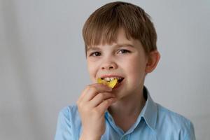 Cerrar retrato alegre niño divirtiéndose comiendo papas fritas aislado foto