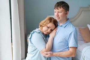 Dreamy couple family connection cuddling looking into distance through window. photo