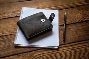 Business and finance concept. View of pen wallet and notebook on wooden table. photo