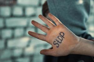 the boy closes his hand, written on his hand stop, cruelty to children photo