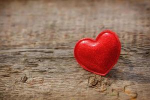 corazón rojo sobre fondo de madera, tarjeta romántica foto