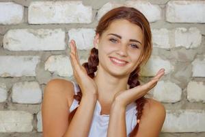 hermosa joven sonriendo con felicidad en el fondo de la pared de ladrillo foto