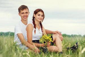 hermosa pareja joven abrazándose en el campo con flores al sol, el concepto de una relación amorosa foto