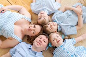 retrato feliz familia caucásica posando en el piso de la casa, acostado en la alfombra foto