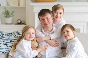 Portrait happy family dad with little children sit relax on couch hugging photo
