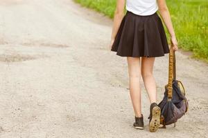 woman walking on the road holding backpack in hand, travel concept, hitchhiking photo