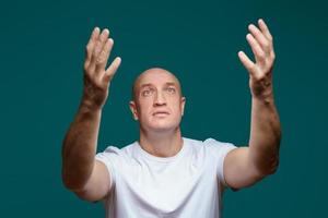 Portrait of a man holding his hands up and looking up, on a blue background photo