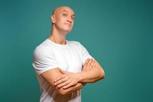 portrait of an emotional bald man in a white t-shirt on a blue background. photo