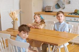 Happy caucasian family with children sitting at kitchen table and drinking photo