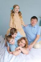 Cheerful family playing together on bed. Parents spend their free time photo