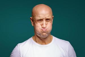 portrait of a bald man puffed out his cheeks on a blue background photo