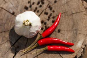 Head of garlic and red hot peppers on a wooden background close-up of a board photo