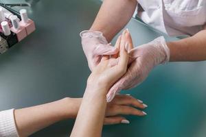 el manicurista hace un masaje manual ligero profesional después del procedimiento de manicura. foto