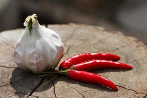 Head of garlic and red hot peppers on a wooden background close-up of a board photo