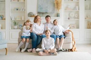 retrato familia numerosa pasando tiempo juntos en casa. están felizmente sentados foto