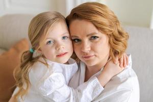 Portrait happy family, single mother and baby daughter hugging on sofa at home photo