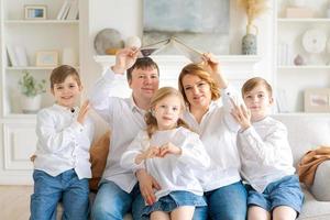 Happy family are sitting in new house in living room on couch holding book photo