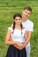joven hermosa pareja linda chica y chico están de pie del brazo en un fondo de la naturaleza, el concepto de la relación foto