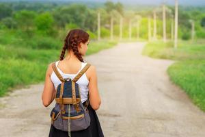 the girl is on the road with a backpack photo
