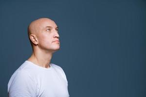 Bald man looking to the side on a blue background photo