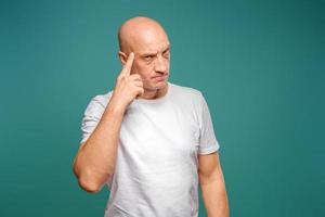 portrait of an emotional bald man in a white t-shirt on a blue background. photo