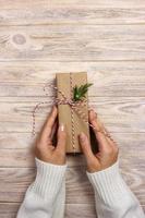 Woman holding a christmas gift in hand on wooden background photo