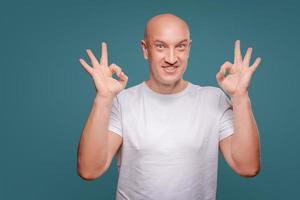 retrato de un hombre alegre que muestra un gesto correcto aislado en el fondo azul foto