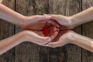 hand in hand on wooden background, heart in hands photo