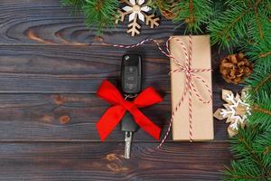 Car key with colorful bow with gift box on wooden background photo