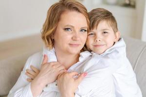 feliz joven madre caucásica abraza a un pequeño y lindo hijo preescolar juntos en casa foto