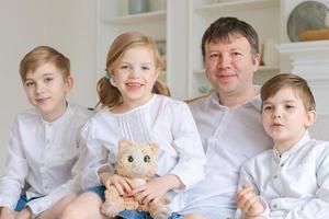 Portrait happy family dad with little children sit relax on couch hugging photo