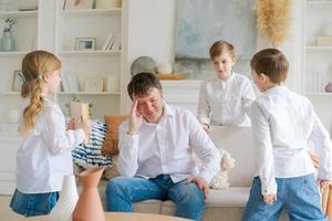 Tired father, sitting on couch in living room, feels annoyed and exhausted photo