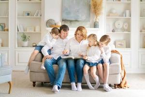 vista frontal gran familia feliz sentados juntos en el sofá, abrazándose unos a otros foto