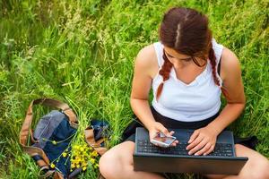 student sitting with a laptop on the grass, top view photo
