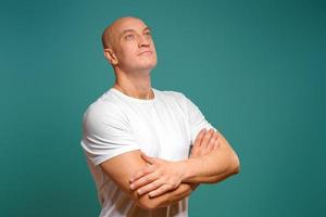 portrait of an emotional bald man in a white t-shirt on a blue background. photo