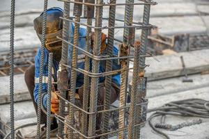 A welder on the construction site makes a metal structure for pouring concrete photo