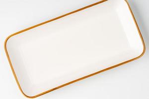 A white ceramic rectangular serving tray with an orange outline. Top view photo