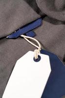 A vertical closeup shot of white blue tags on a string on a cloth with a blank blue tag on the neck photo