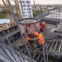 The workers on a building infrastructure roof with machinery and tools. Pouring concrete into a mold photo