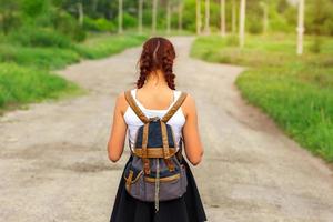 the girl is on the road with a backpack photo