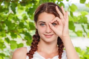 cheerful smiling girl shows hand gesture all OK in nature photo