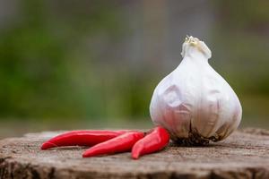 Head of garlic and red hot peppers on a wooden background close-up of a board photo